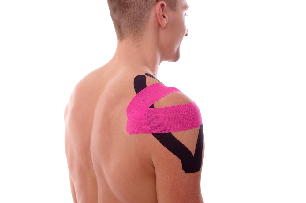 Kinesiology tape guide: How to tape shoulder with kinesiology tape. Shoulder  pain treatment. Shirtless man on white backgorund. Side-back viewpoint.